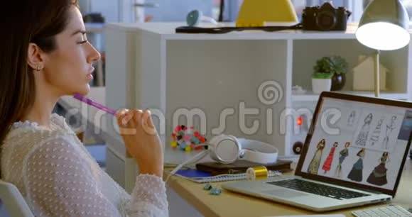 高加索女时装设计师在办公室办公桌上电脑工作的侧视图视频的预览图