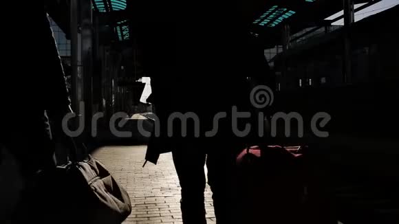在最后的阳光下两个带着旅行袋的人站在火车站的站台上视频的预览图