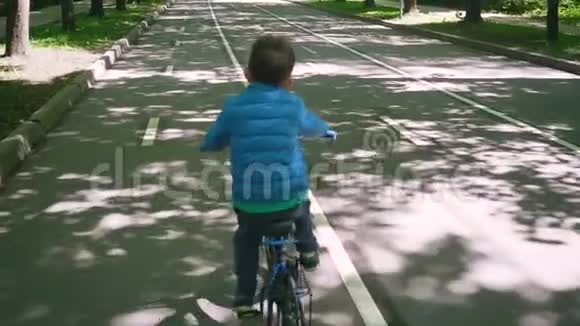 在城市公园里骑蓝色自行车的小男孩视频的预览图