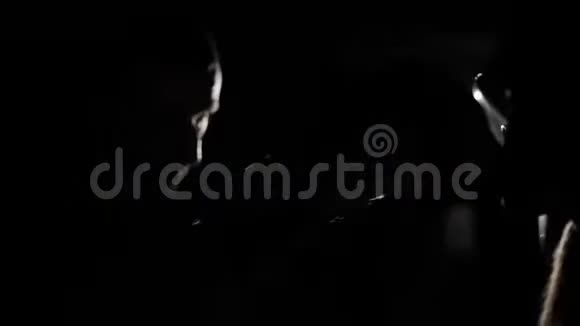 拳击手戴拳击手套与教练练习拳打脚踢的男拳击手的特写黑暗的背景照相机灯光反射视频的预览图