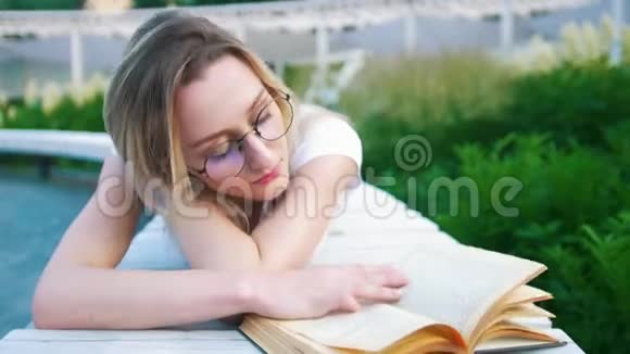 美丽的年轻女子躺在城市花园看书视频的预览图