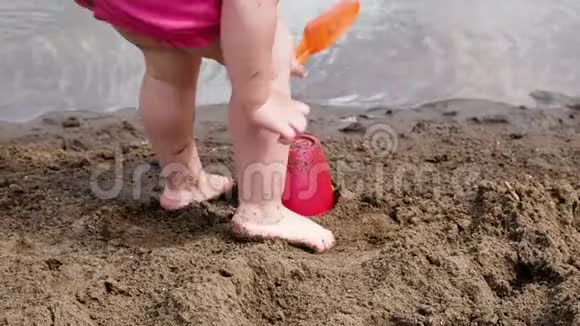 小女孩在桶上敲桨动作慢孩子们在沙滩上玩自然游戏视频的预览图