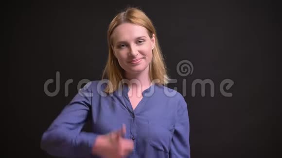 年轻的白种人金发女人的肖像用手指示意以显示喜欢和尊重的黑色背景视频的预览图