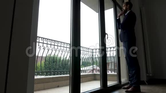 全身商人站在办公室的大窗户前视频的预览图