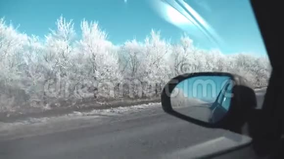 从车窗上看到的景色白雪覆盖的道路和霜冻的树木一个美丽的冬日视频的预览图
