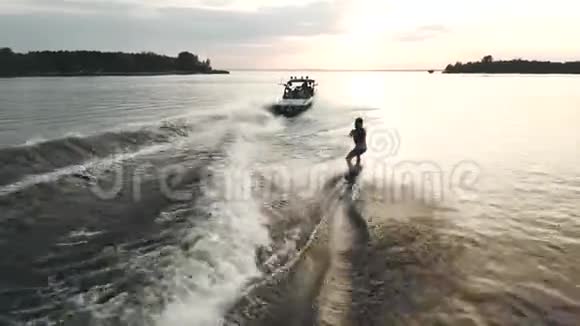 在船后冲浪的船上飞行日落时在河上醒来的鸟瞰图视频的预览图
