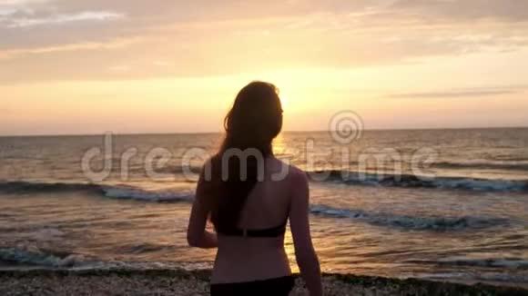 穿黑色泳衣的时髦女孩在日落时进入大海我对大海和海滩很满意关于视频的预览图