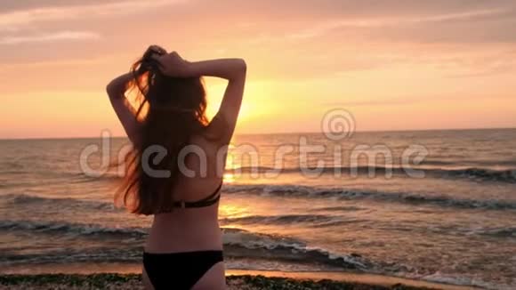 穿黑色泳衣的时髦女孩在日落时进入大海我对大海和海滩很满意关于视频的预览图