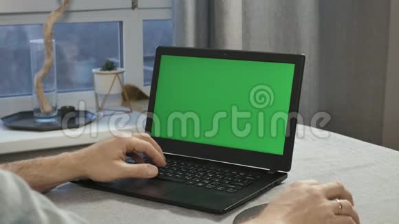 在带有绿色屏幕的笔记本电脑上工作的男性手的特写视频的预览图