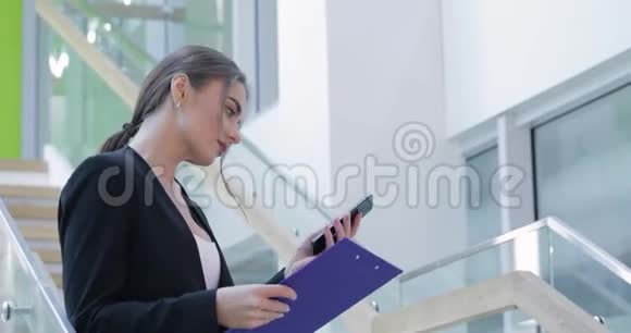 商务女性在办公中心的楼梯上使用手机视频的预览图