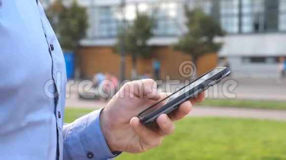 年轻商人手持和触摸智能手机站在城市街道上的面目全非的男人视频的预览图