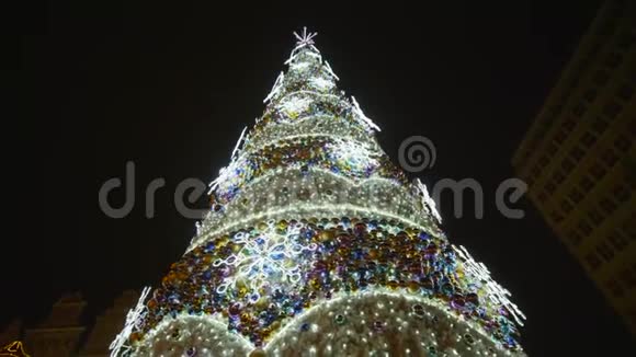 美丽的圣诞树装饰着明亮的闪闪发光的花环和玩具在城市广场上在夜空中度假视频的预览图
