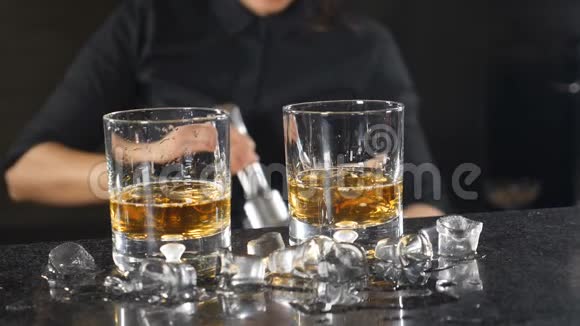 夜总会里的夜生活女酒保在酒杯里准备酒精鸡尾酒使冰块缓慢运动冰冰视频的预览图