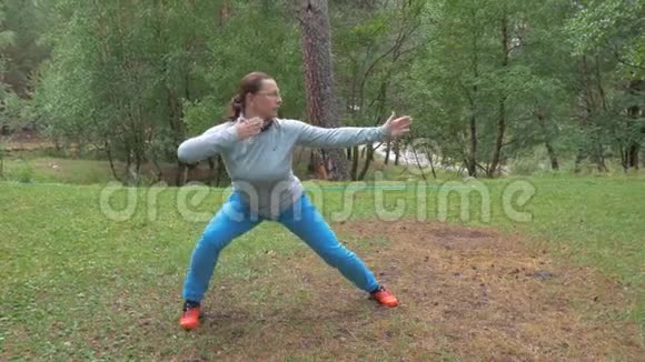 一个女人正在森林里的空地上做东方运动瑜伽和冥想健康的生活方式慢慢慢慢视频的预览图