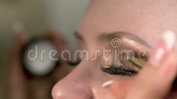 化妆师用画笔将明亮的眼妆涂在的眼睛上最接近的视角视频的预览图