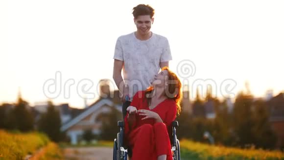 微笑的年轻人在轮椅上摇着一个红发女孩谁告诉他什么视频的预览图