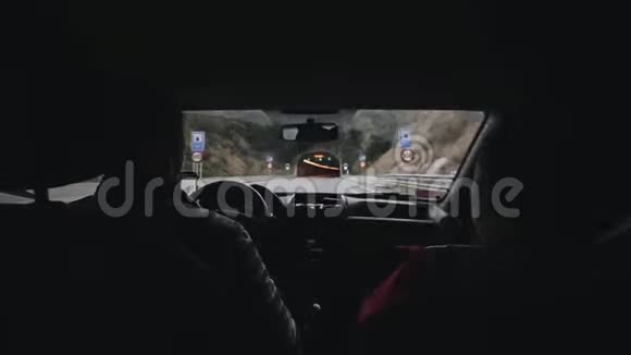 一对家庭夫妇乘汽车旅行穿过一条长长的黑暗的汽车隧道从汽车后座看风景视频的预览图