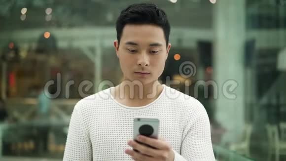慢动作中镜头亚洲男性走路带手机在窗口背景视频的预览图