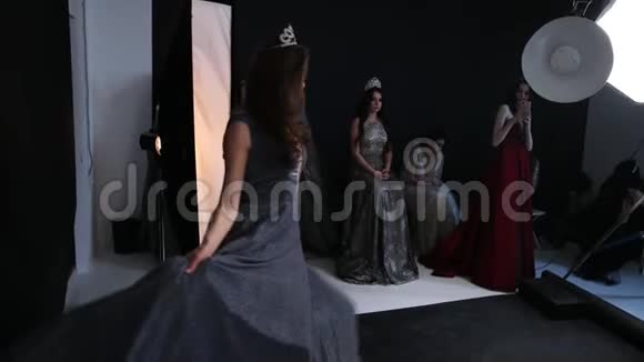 摄影师在摄影棚里拍摄女模特黑发身穿灰色连衣裙视频的预览图