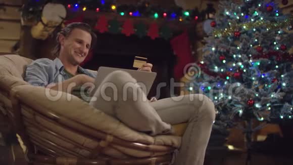 圣诞夜帅哥一边上网一边用笔记本电脑和信用卡聊天视频的预览图