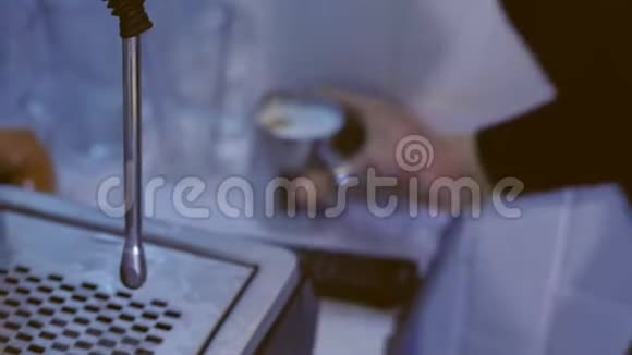 专业男咖啡师准备新鲜咖啡卡布奇诺与蒸汽发生器持有水罐双手特写视频的预览图