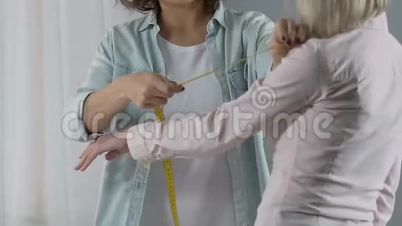 微笑设计师测量女性顾客手臂讨论着装顺序视频的预览图