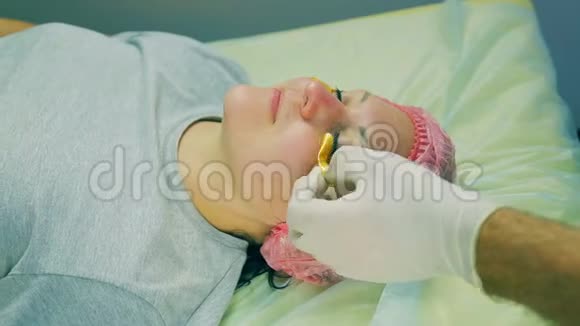 戴着手套的化妆师的男人的手从女人的脸上移开眼睛下面的胶原蛋白垫视频的预览图