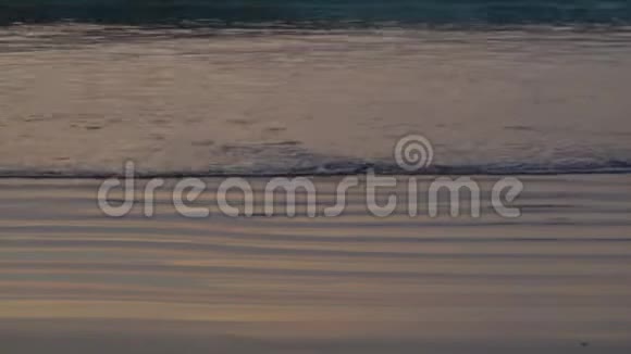 4K在热带海滩上惊人的日落日落时海滩上的海水波浪阳光反射水面视频的预览图