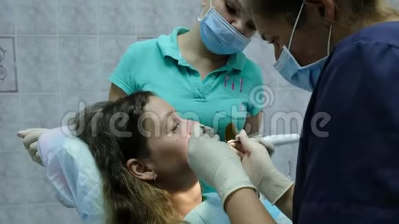 去看牙医牙齿矫正医生协助为一名有固定牙器的妇女安装铁支架视频的预览图