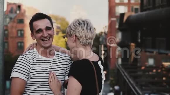 慢动作快乐的西班牙男人和欧洲女孩在纽约夏天的一座大城市桥上谈笑风生视频的预览图