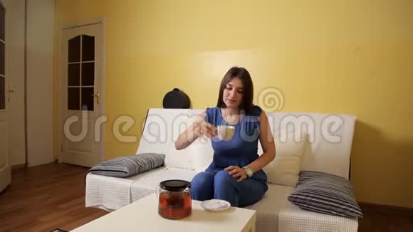 一个穿着蓝色西装的年轻女孩坐在沙发上快速地喝着茶上班迟到逃跑了视频的预览图