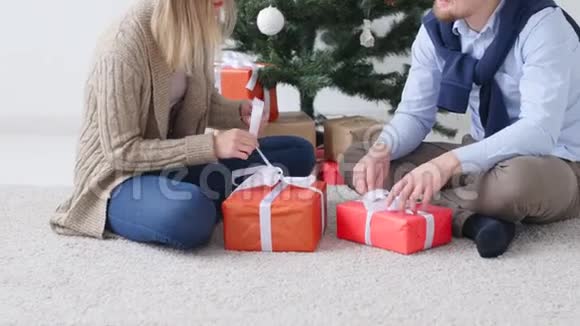 年轻幸福的一对夫妇在一个白色的房间里打开圣诞礼物视频的预览图