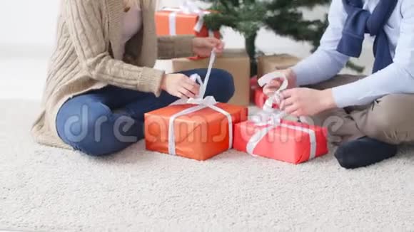 年轻幸福的一对夫妇在一个白色的房间里打开圣诞礼物视频的预览图