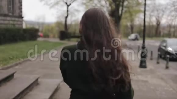 一位美丽的年轻女孩留着棕色长发在春天散步慢动作视频的预览图