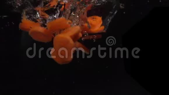 慢动作切碎的胡萝卜掉进水里溅在黑色背景下烹饪蔬菜视频的预览图