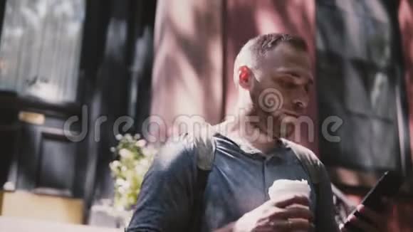 忙碌的英俊的欧洲男人走在布鲁克林房子的楼梯上带着智能手机和咖啡慢动作特写视频的预览图