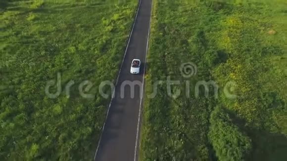 空中拍摄白色敞篷车骑过空的乡村道路四位年轻的无法辨认的女性视频的预览图