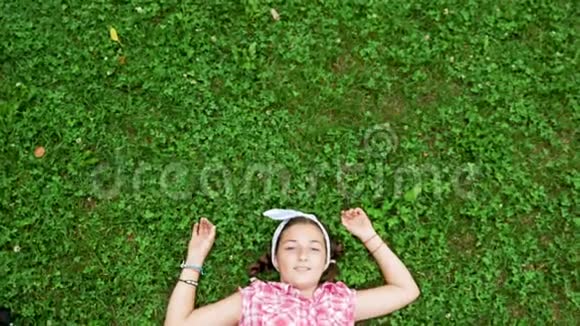 美丽的少女躺在公园的草地上视频的预览图