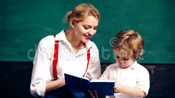 老师和男孩写在笔记本上坐在学校教室里背景是绿色的学校董事会学习视频的预览图