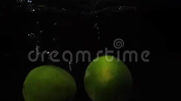 两个青柠扔进盛水的容器里慢动作水果视频食物录像视频的预览图