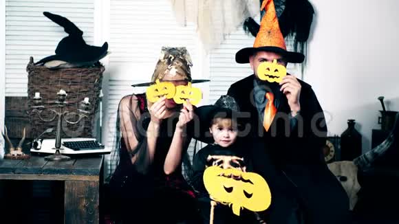这个男孩他的父母穿着女巫骷髅和女巫的西装用甜瓜遮住他们的脸穿着服装的家人视频的预览图