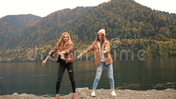 两个女孩在湖上的背景下在山上跳舞为博客而笑社交媒体旅游博客视频的预览图