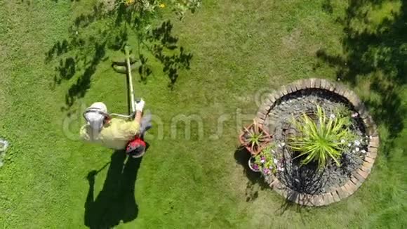 园丁在花园的树下割草视频的预览图
