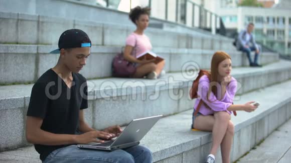 青年学生打字笔记本电脑坐在校园楼梯数字世代自由职业视频的预览图