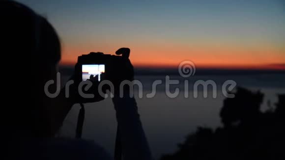 女专业摄影师拍摄海上美丽的日落游客制作自然视频与单反相机特拉夫视频的预览图