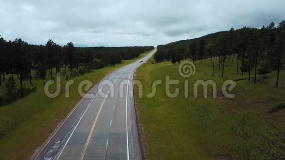 静止无人机拍摄的交通汽车沿混凝土公路之间的野生绿色森林岩石山在阴天视频的预览图