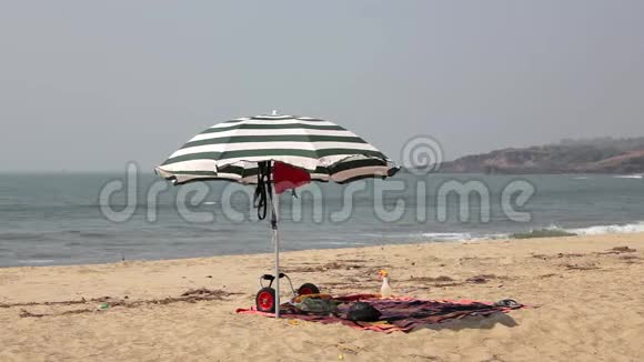 在蓝色海浪的背景下沙滩上有一把黑白大伞视频的预览图