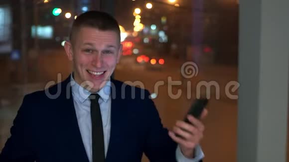 这位男商人看着智能手机高兴高兴窗外对着夜城视频的预览图