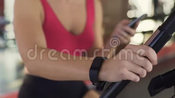 健身器材苗条的女人带着腕带骑在健身车上视频的预览图