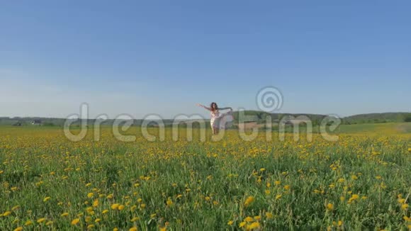 一个穿着衣服的女人在一片野花盛开的田野里奔跑举起双臂视频的预览图